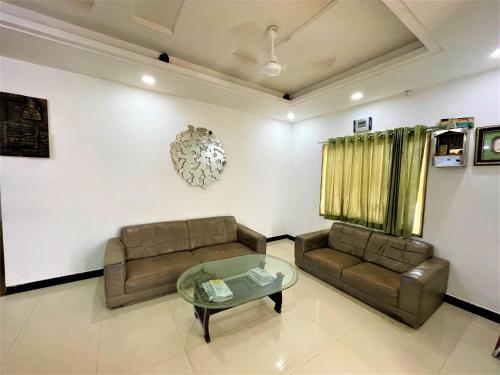 a living room with two couches and a glass table at Usha Residency in Bhuj