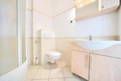 a white bathroom with a sink and a toilet at Promenada I, Sun & Snow in Świnoujście