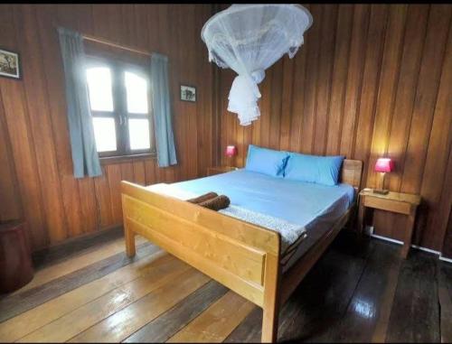 Ce lit se trouve dans une chambre en bois dotée d'une fenêtre. dans l'établissement Ratanakiri Lakeside Homestay & Tours, à Banlung