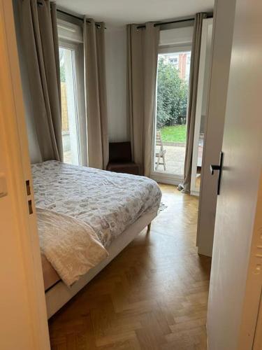 - une chambre avec un lit et une porte donnant sur un balcon dans l'établissement Appartement confort avec Jardin, à Saint-Denis