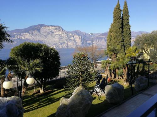 uma vista para as montanhas a partir de um jardim com árvores em Hotel Drago - Garda Lake Collection em Brenzone sul Garda
