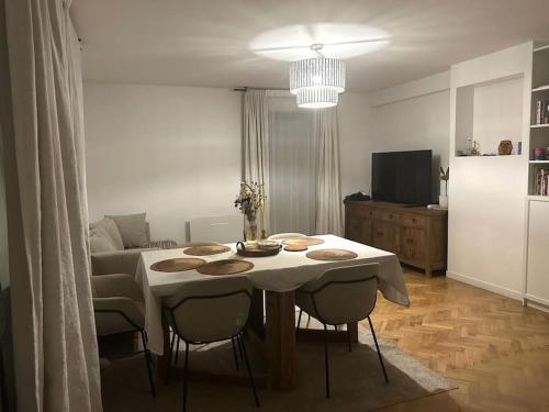 un salon avec une table et des chaises blanches dans l'établissement Appartement confort avec Jardin, à Saint-Denis