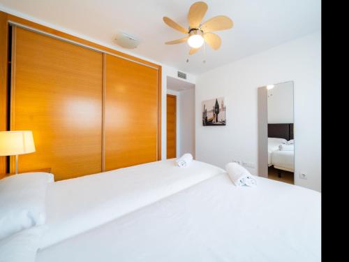 een slaapkamer met 2 witte bedden en een houten hoofdeinde bij Sun and Golf Apartment by Rentalole in Torre-Pacheco