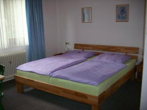 a bedroom with a wooden bed with purple sheets at abmelden das unterkunft in Bad Rappenau