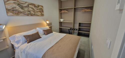 um quarto com uma grande cama branca e prateleiras em APARTAMENTOS TURISTICOS LOS ROQUES em Cáceres