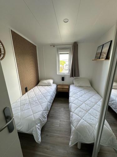 deux lits dans une chambre avec une fenêtre dans l'établissement Chalet pour 6 - Domaine avec piscine chauffée, à Bretignolles-sur-Mer