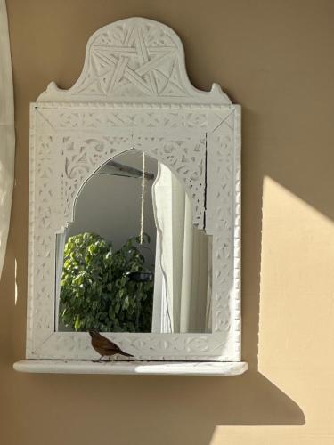 uno specchio con cornice bianca su un muro di Riad Zeitoun Palace a Marrakech