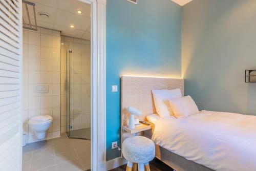 a bedroom with a bed and a shower and a toilet at City Hotel Rembrandt in Leiden