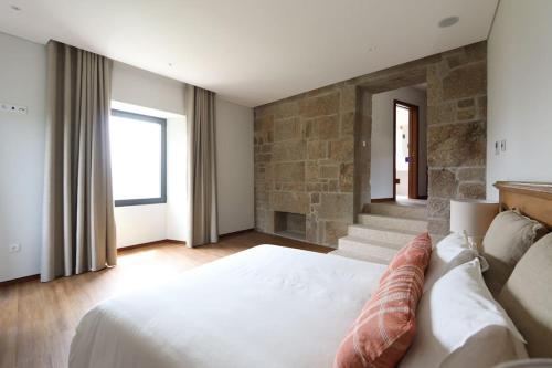a bedroom with a large bed and a stone wall at Quinta de Travanca - Casa do Páteo, Baião, Douro in Baião