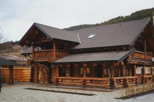 a large wooden building with a black roof at Hanul lui Mujdei in Vatra Dornei