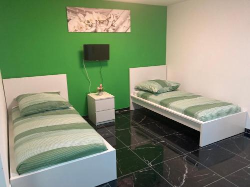 2 camas en una habitación con paredes verdes en Sofa Apartment, en Seeheim-Jugenheim