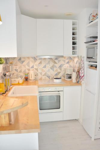 une cuisine blanche avec des armoires blanches et un évier dans l'établissement Grand appartement pour 8 - La Baule-Escoublac, à La Baule