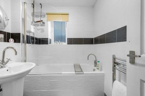 a white bathroom with a sink and a bath tub at 2 Bedroom Apartment on South Beach Road, Ayr in Ayr