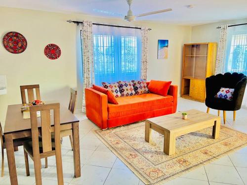 ein Wohnzimmer mit einem roten Sofa und einem Tisch in der Unterkunft Autumn House DIani in Ukunda
