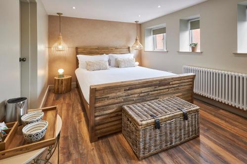 a bedroom with a large bed with a wicker trunk at The Believe Boutique (Believe Bar & Bedrooms) in Redcar