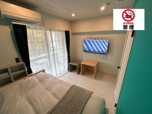 a bedroom with a bed and a tv on the wall at Hotel 螢月ｰhozukiｰ Adult Only in Sendai
