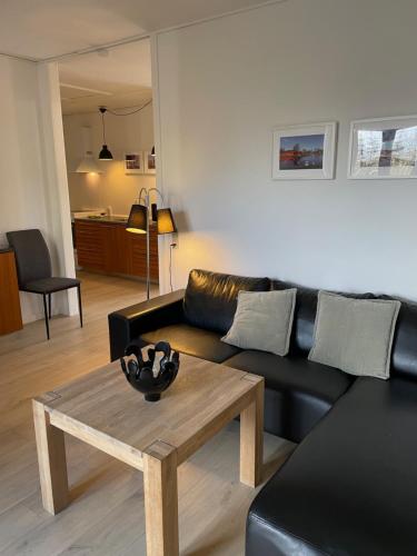 a living room with a black couch and a coffee table at Søhusets anneks1 in Viborg