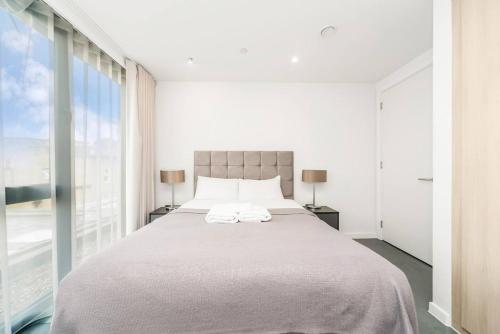 een witte slaapkamer met een groot bed met 2 lampen bij Pass The Keys Plush Perfection in Londen