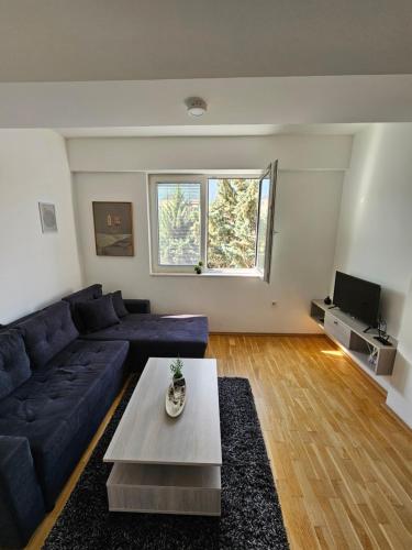 ein Wohnzimmer mit einem blauen Sofa und einem Tisch in der Unterkunft DDApartment in Skopje