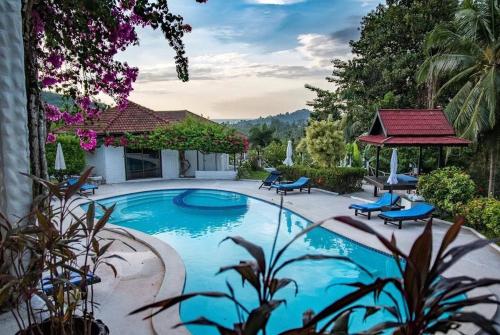 una piscina con sillas azules y una casa en La Casa Bianca Samui, en Nathon Bay