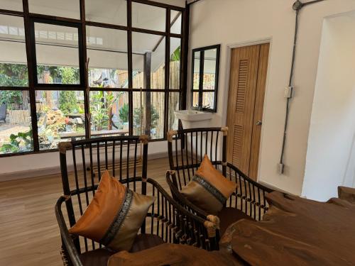 twee stoelen met kussens in een kamer met ramen bij Proud Chiang Mai Poshtel in Chiang Mai