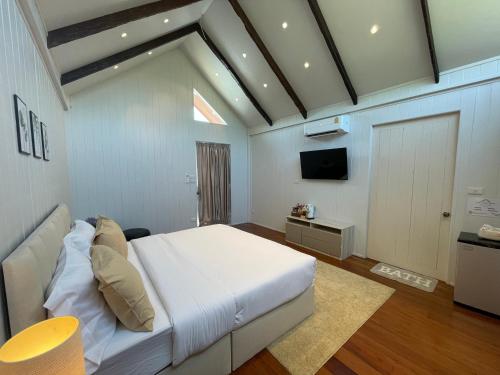 a bedroom with a white bed and a tv at The Organic Farmstay Khoa Yai (ดิ ออร์แกนิค ฟาร์มสเตย์ เขาใหญ่) in Wangkata