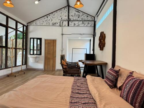 um quarto com uma cama grande e uma mesa em Proud Chiang Mai Poshtel em Chiang Mai