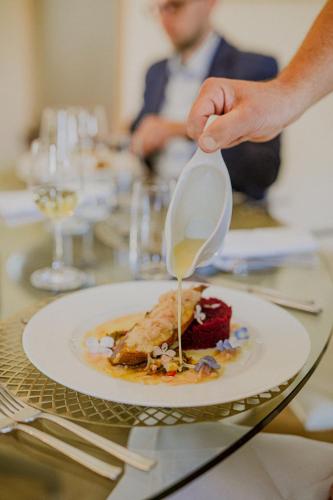 a person holding a spoon over a plate of food at Pałac Pakoszów Schlosshotel Wernersdorf in Jelenia Góra