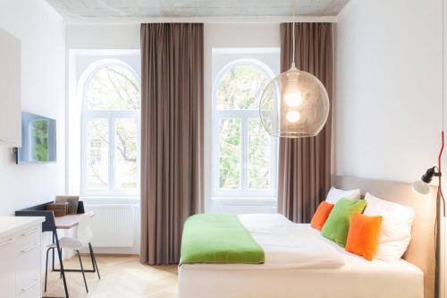 um quarto com uma cama branca e almofadas coloridas em KS70 Apartments em Viena