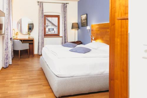 a bedroom with a large white bed and a desk at Hotel Kaiserhof in Anif