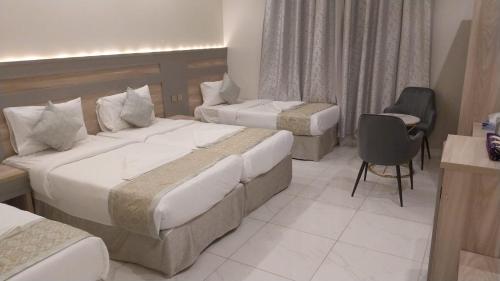 a hotel room with two beds and a chair at فندق الروابط نفحات الحرم سابقا in Makkah
