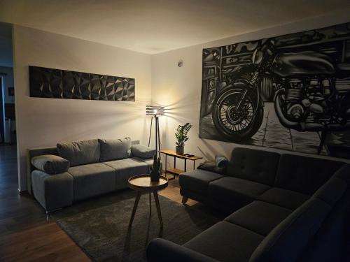 una sala de estar con sofá y una pintura de motocicleta en la pared en Tölgyes Apartmanház, en Szeged