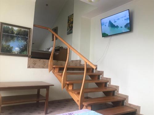 Una escalera de madera en una habitación con TV en la pared en Adonis en Úzhgorod