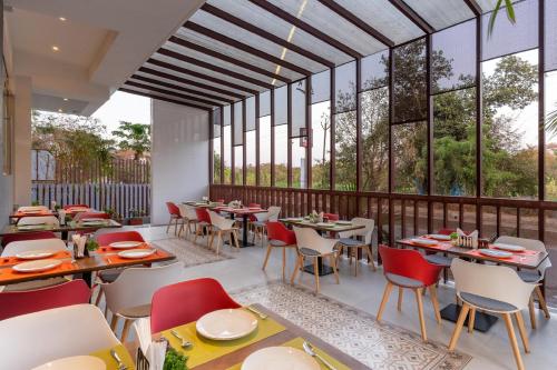 ein Restaurant mit Tischen, Stühlen und Fenstern in der Unterkunft The Royal Pavilion, Kolhapur in Kolhapur