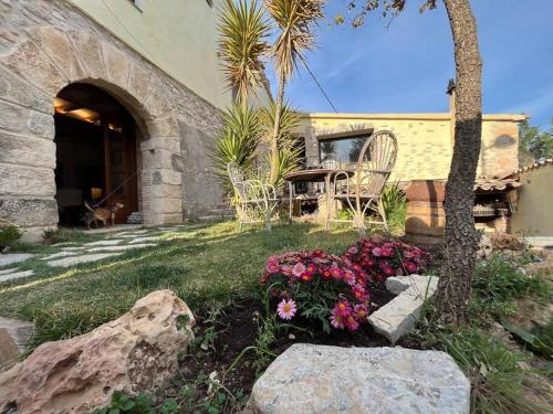 un jardín con flores frente a un edificio en Can Óscar Rural Casa con piscina y barbacoa ideal para famílias en Mediona