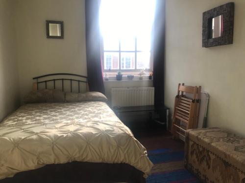 um quarto com uma cama e uma janela em Guinness Court Shared Apartment em Londres