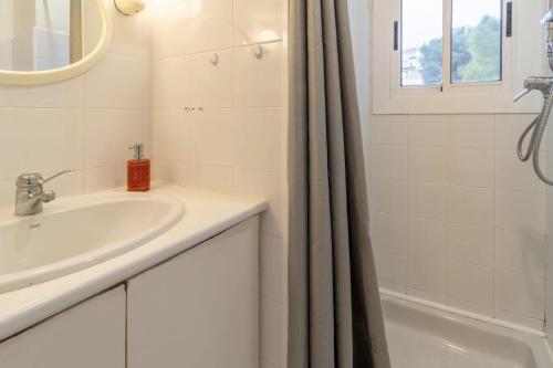La salle de bains blanche est pourvue d'un lavabo et d'une baignoire. dans l'établissement Les Tonyines 67 Apartamento con vistas y terraza, à Llançà
