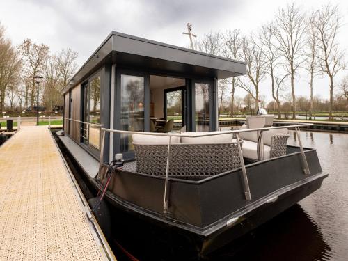 a black boat in the water next to a dock at Houseboat in Offingawier with Sea View in Offingawier