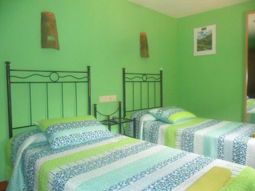 two beds in a room with green walls at La Jelechera in El Gasco