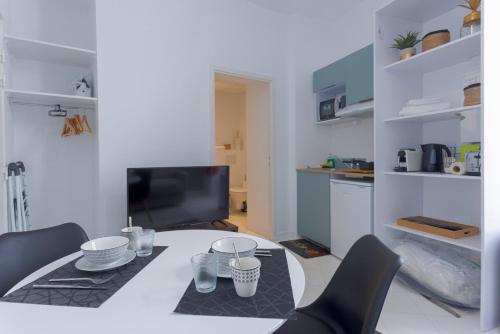 un salon avec une table, des chaises et une télévision dans l'établissement LE MIMONT studio central et calme, séjours en couple ou congrès, à Cannes