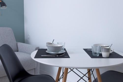 une table blanche avec deux assiettes et des tasses dessus dans l'établissement LE MIMONT studio central et calme, séjours en couple ou congrès, à Cannes