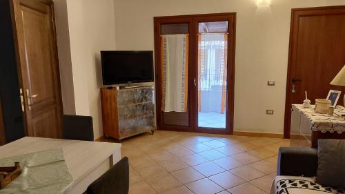 a living room with a television and a living room with a table at Sara Sole & Mare in Torpè