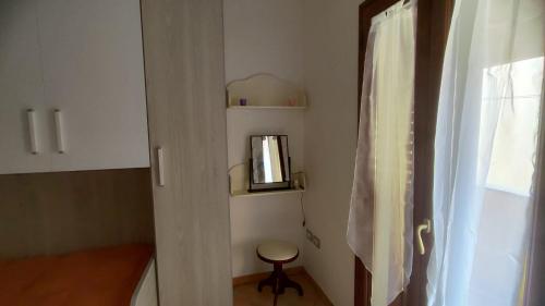 a small bathroom with a stool next to a window at Sara Sole & Mare in Torpè
