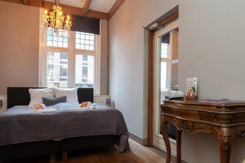 a bedroom with a bed and a table and windows at Kings Inn City Hotel Alkmaar in Alkmaar