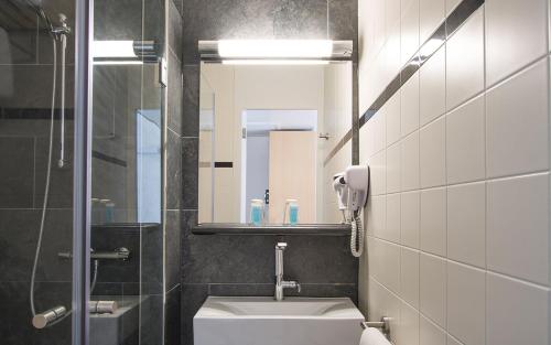 a bathroom with a sink and a toilet and a mirror at Bastion Hotel Rotterdam Zuid in Rotterdam