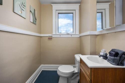 a bathroom with a toilet and a sink and a window at Charming 4BR Westside Home in Beer City USA in Grand Rapids