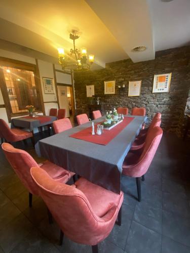 a dining room with a long table and pink chairs at Hotel Hieronimi in Cochem