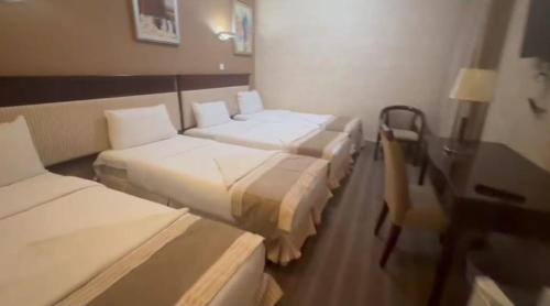 a hotel room with three beds and a desk at Arfalon Hotel and Tourism in Makkah