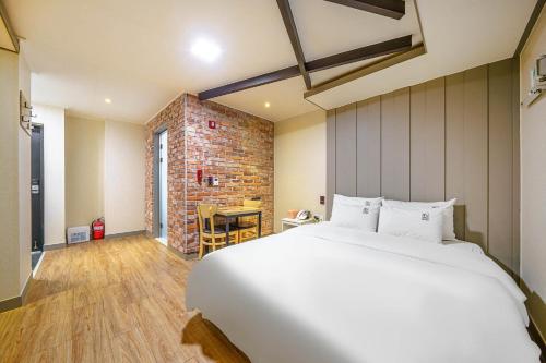 um quarto com uma grande cama branca e uma parede de tijolos em Number 25 Gyeongju City Hall em Gyeongju