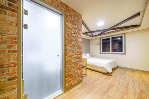 a bedroom with a bed and a brick wall at Number 25 Gyeongju City Hall in Gyeongju